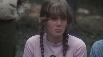Movie still from “Cockfighter” (1974), directed by Monte Hellman – A woman with two braids sitting in front of a tree; Close Up shot, Low angle