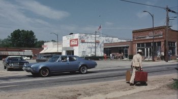 Movie still from “Cockfighter” (1974), directed by Monte Hellman – A man walking down a street with a suitcase; Extreme Wide shot, High angle