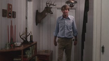 Movie still from “Cockfighter” (1974), directed by Monte Hellman – A man standing in front of a door in a room; Medium shot, Low angle
