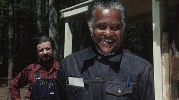 Movie still from “Cockfighter” (1974), directed by Monte Hellman – Two men standing next to each other in front of a building; Medium shot, Low angle