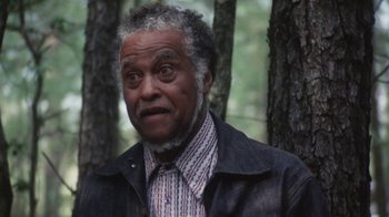 Movie still from “Cockfighter” (1974), directed by Monte Hellman – An older man in a jacket and tie in the woods; Close Up shot, Over the shoulder angle