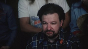 Movie still from “Cockfighter” (1974), directed by Monte Hellman – A person wearing a plaid shirt; Close Up shot, Over the shoulder angle