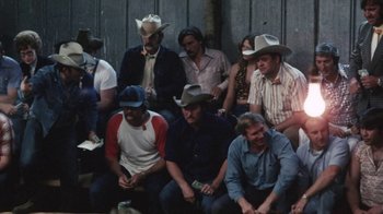 Movie still from “Cockfighter” (1974), directed by Monte Hellman – A group of men sitting in a row wearing cowboy hats; Wide shot, High angle