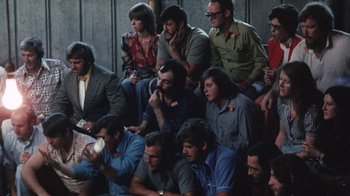 Movie still from “Cockfighter” (1974), directed by Monte Hellman – A group of people sitting in a room; Wide shot, High angle