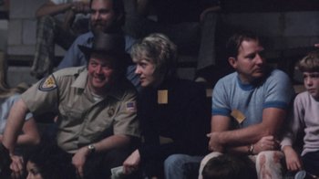 Movie still from “Cockfighter” (1974), directed by Monte Hellman – A group of people sitting next to each other in a room; Medium shot, High angle