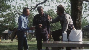Movie still from “Cockfighter” (1974), directed by Monte Hellman – A group of men standing around a picnic table; Medium shot, High angle