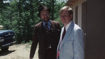 Movie still from “Cockfighter” (1974), directed by Monte Hellman – Two men in suits standing next to each other outside; Medium shot, Over the shoulder angle