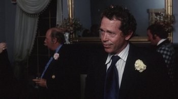 Movie still from “Cockfighter” (1974), directed by Monte Hellman – A man in a suit and tie standing next to another man in a suit and tie; Close Up shot, Over the shoulder angle