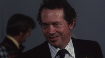 Movie still from “Cockfighter” (1974), directed by Monte Hellman – A person wearing a suit and tie; Close Up shot, Over the shoulder angle