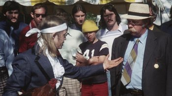 Movie still from “Cockfighter” (1974), directed by Monte Hellman – A group of people standing around a woman; Medium shot, Over the shoulder angle