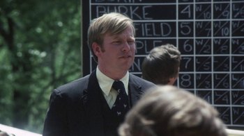 Movie still from “Cockfighter” (1974), directed by Monte Hellman – A man in a suit and tie standing in front of a chalkboard; Close Up shot, Over the shoulder angle