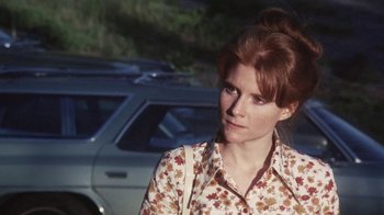Movie still from “Cockfighter” (1974), directed by Monte Hellman – A woman with red hair standing in front of a car; Close Up shot, Over the shoulder angle