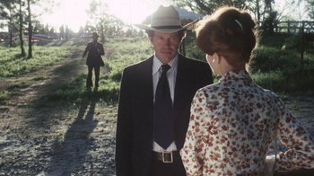 Movie still from “Cockfighter” (1974), directed by Monte Hellman – A man in a suit and a hat talking to a woman in a dress; Medium shot, Over the shoulder angle