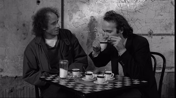 Movie still from “Coffee and Cigarettes” (2003), directed by Jim Jarmusch – Two men are sitting at a table drinking coffee; Medium shot, Over the shoulder angle