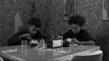 Movie still from “Coffee and Cigarettes” (2003), directed by Jim Jarmusch – A couple of people sitting at a dinner table; Medium shot, High angle