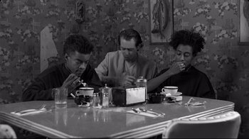 Movie still from “Coffee and Cigarettes” (2003), directed by Jim Jarmusch – A group of people sitting at a table eating food; Medium shot, Low angle