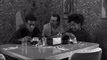 Movie still from “Coffee and Cigarettes” (2003), directed by Jim Jarmusch – A man and two young boys sitting at a dinner table; Medium shot, Over the shoulder angle