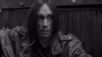 Movie still from “Coffee and Cigarettes” (2003), directed by Jim Jarmusch – Black and white photograph of a man with long black hair; Close Up shot, Over the shoulder angle