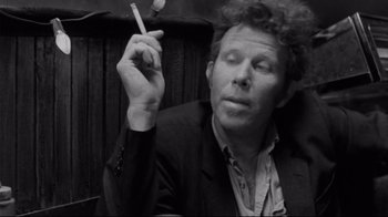 Movie still from “Coffee and Cigarettes” (2003), directed by Jim Jarmusch – Black and white photograph of a man smoking a cigarette; Close Up shot, Low angle