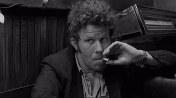 Movie still from “Coffee and Cigarettes” (2003), directed by Jim Jarmusch – Black and white photograph of a man smoking a cigarette; Close Up shot, Low angle