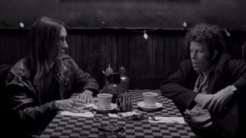 Movie still from “Coffee and Cigarettes” (2003), directed by Jim Jarmusch – Two people sitting at a table with cups of coffee; Medium shot, High angle