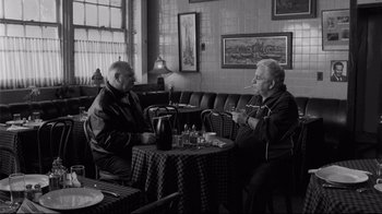 Movie still from “Coffee and Cigarettes” (2003), directed by Jim Jarmusch – Two older men sitting at a table in a restaurant; Wide shot, High angle