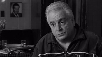 Movie still from “Coffee and Cigarettes” (2003), directed by Jim Jarmusch – An older man sitting at a table in a restaurant; Close Up shot, High angle