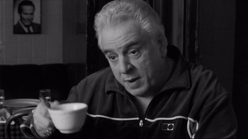 Movie still from “Coffee and Cigarettes” (2003), directed by Jim Jarmusch – An older man sitting in front of a cup of coffee; Close Up shot, Low angle