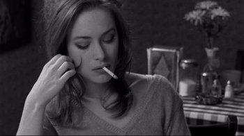 Movie still from “Coffee and Cigarettes” (2003), directed by Jim Jarmusch – A young woman smoking a cigarette in a room; Close Up shot, High angle
