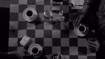 Movie still from “Coffee and Cigarettes” (2003), directed by Jim Jarmusch – A black - and - white photo of a table with cups of coffee; Extreme Close Up shot, Overhead angle