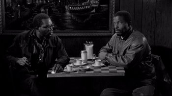 Movie still from “Coffee and Cigarettes” (2003), directed by Jim Jarmusch – Two men sitting at a table with cups of coffee; Medium shot, Over the shoulder angle