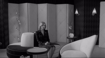 Movie still from “Coffee and Cigarettes” (2003), directed by Jim Jarmusch – A black and white photo of a woman sitting on a chair; Wide shot, Over the shoulder angle
