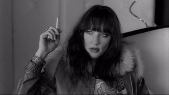 Movie still from “Coffee and Cigarettes” (2003), directed by Jim Jarmusch – A woman holding a cigarette in her right hand; Close Up shot, High angle