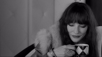 Movie still from “Coffee and Cigarettes” (2003), directed by Jim Jarmusch – A black and white photo of a woman holding a coffee cup; Close Up shot, High angle