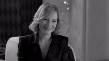 Movie still from “Coffee and Cigarettes” (2003), directed by Jim Jarmusch – A black and white photo of a woman smiling for the camera; Close Up shot, Over the shoulder angle