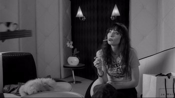 Movie still from “Coffee and Cigarettes” (2003), directed by Jim Jarmusch – A woman sitting on the ground smoking a cigarette; Medium shot, High angle