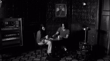 Movie still from “Coffee and Cigarettes” (2003), directed by Jim Jarmusch – A man and a woman sitting at a table; Wide shot, Low angle