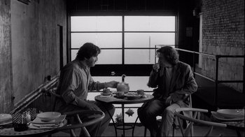Movie still from “Coffee and Cigarettes” (2003), directed by Jim Jarmusch – Two men are sitting at a table and drinking tea; Medium shot, Over the shoulder angle