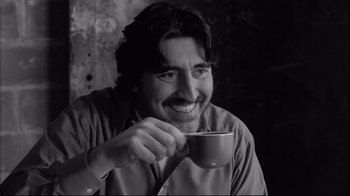 Movie still from “Coffee and Cigarettes” (2003), directed by Jim Jarmusch – A black and white photo of a man holding a coffee cup; Close Up shot, Low angle