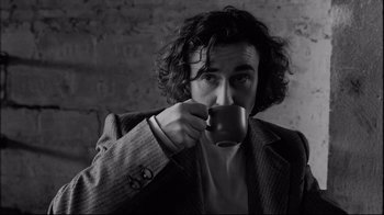 Movie still from “Coffee and Cigarettes” (2003), directed by Jim Jarmusch – A man in a suit holding a coffee cup; Close Up shot, Low angle