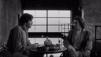 Movie still from “Coffee and Cigarettes” (2003), directed by Jim Jarmusch – Two people sitting at a table with a tea pot; Medium shot, Over the shoulder angle