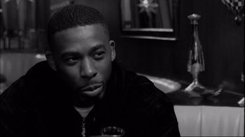 Movie still from “Coffee and Cigarettes” (2003), directed by Jim Jarmusch – A black and white photo of a man in a black jacket; Close Up shot, Over the shoulder angle