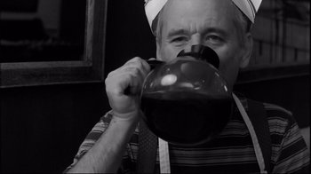 Movie still from “Coffee and Cigarettes” (2003), directed by Jim Jarmusch – A man drinking from a coffee pot in a kitchen; Close Up shot, Low angle