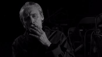 Movie still from “Coffee and Cigarettes” (2003), directed by Jim Jarmusch – A man smoking a cigarette while holding his hands to his mouth; Close Up shot, Low angle