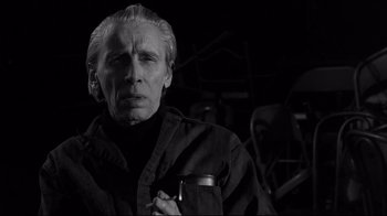 Movie still from “Coffee and Cigarettes” (2003), directed by Jim Jarmusch – An older man holding a cell phone while standing in a dark room; Close Up shot, Low angle