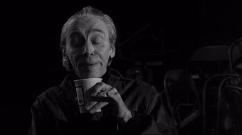 Movie still from “Coffee and Cigarettes” (2003), directed by Jim Jarmusch – An older man holding a coffee cup in his hands; Close Up shot, Low angle