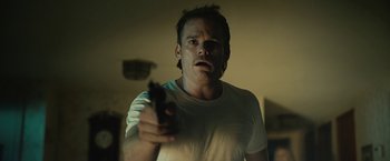 Movie still from “Cold in July” (2014), directed by Jim Mickle – A man holding a gun in a room; Close Up shot, Low angle