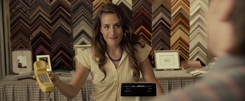 Movie still from “Cold in July” (2014), directed by Jim Mickle – A woman standing in front of a wall of picture frames; Close Up shot, Over the shoulder angle