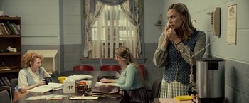 Movie still from “Cold in July” (2014), directed by Jim Mickle – Two women sitting at a table in front of a window; Medium shot, Over the shoulder angle