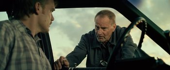 Movie still from “Cold in July” (2014), directed by Jim Mickle – An older man looking at a younger man in a car; Close Up shot, Over the shoulder angle